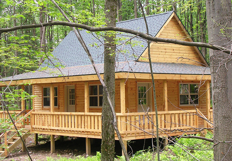 land and cabins for sale ny state image of wraparound cabin with porch and windows surrounded by trees