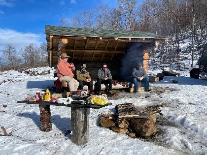 family outside in winter at camp enjoying food 